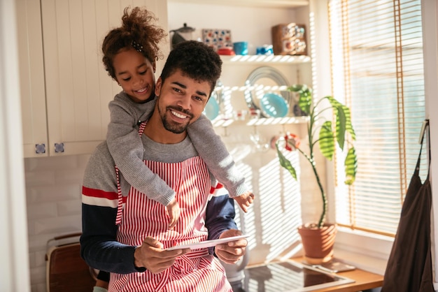 Afroamerikanischer Vater und seine Tochter lesen ein Rezept in der Küche.