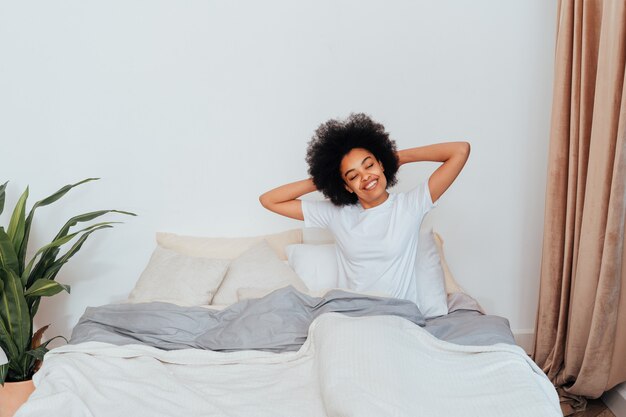 Afroamerikanisches Mädchen, das zu Hause im Bett ruht - Schöne Frau, die sich zu Hause entspannt