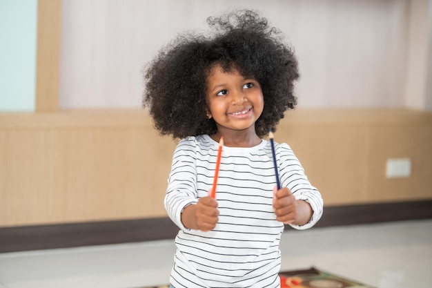 Afroamerikanisches Mädchen hält einen Bleistift. Schul-Nerd aufgeregtes schwarzes Schulmädchen mit Bleistift