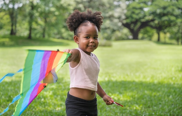 Foto afroamerikanisches mädchen spielt drachen im park