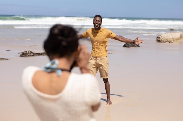 Afroamerikanisches Paar fotografiert mit der Kamera an einem Strand am Meer. gesunder Lebensstil, Freizeit in der Natur.