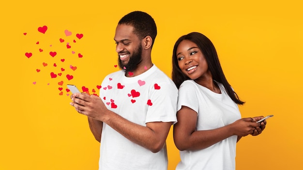 Afroamerikanisches Paar mit Smartphones, das Liebesbotschaften sendet