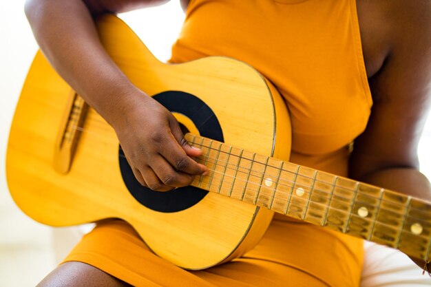 Afroamerikanisches Teenager-Mädchen, das ihre Fähigkeiten auf der Akustikgitarre übt