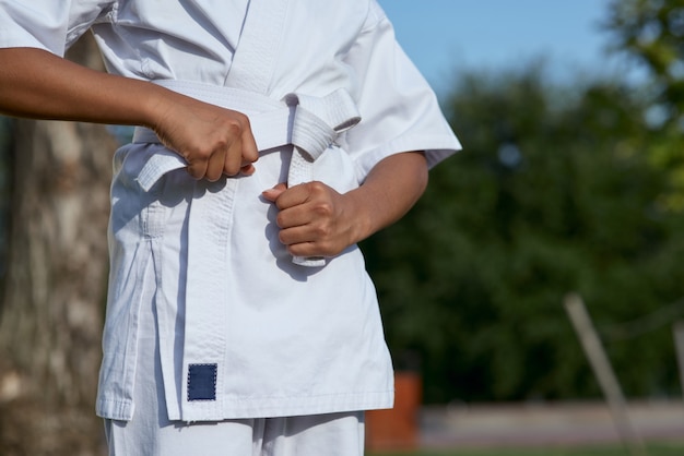 Afroamerikanisches Tittle-Mädchen, das Gürtel auf Karate-Kimono bindet