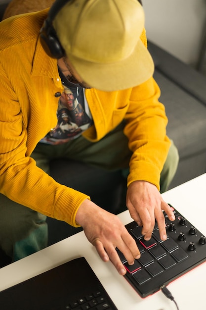 Afrobrasilianischer Mann, der mit einem MPD-MIDI-Controller von seinem Sofa am Couchtisch aus Beats macht