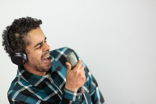 Afrobrasilianischer Mann in kariertem Hemd, der in ein Kondensatormikrofon singt