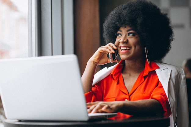 Afroe-amerikanisch Geschäftsfrau, die an einem Telefon in einem Café spricht