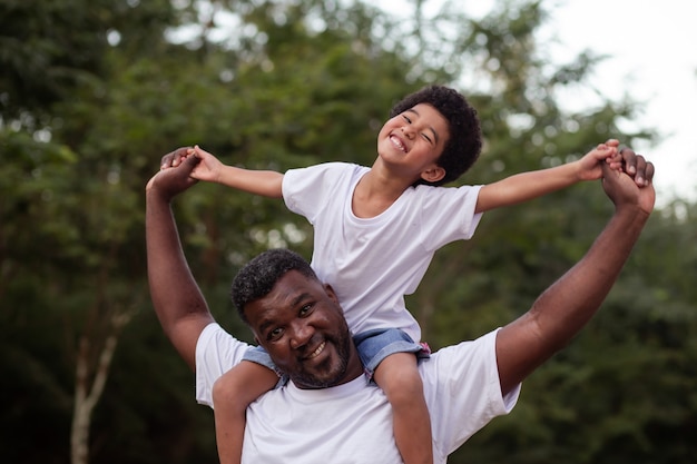 Afrojunge mit seinem Vater im Park am Hals