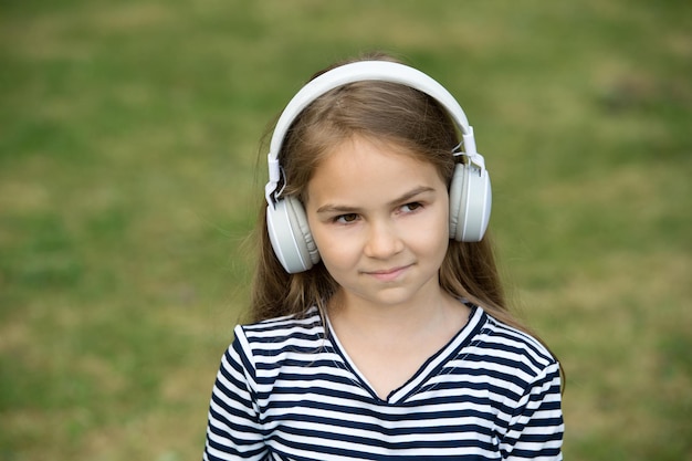 Afrontar las consecuencias. Niña escucha música al aire libre. Los niños pequeños usan auriculares tocando música. Nueva tecnología. Vida moderna. Vacaciones de verano. Diversión y entretenimiento. Oírlo.