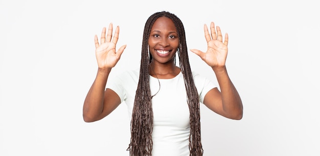 Afroschwarze erwachsene Frau, die lächelt und freundlich aussieht, die Nummer zehn oder zehn mit der Hand nach vorne zeigt und herunterzählt