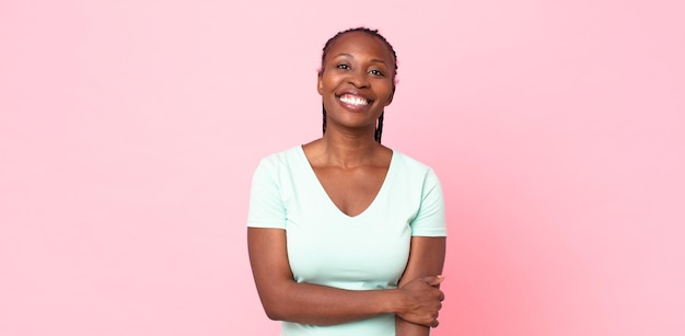 Afroschwarze erwachsene Frau, die schüchtern und fröhlich lacht, mit einer freundlichen und positiven, aber unsicheren Haltung