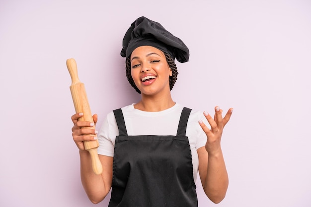 Afroschwarze Frau, die sich glücklich fühlt, überrascht, eine Lösung oder Idee zu verwirklichen. Koch mit einem Rollstift