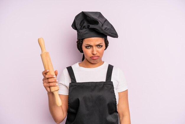 Foto afroschwarze frau, die sich traurig und weinerlich fühlt, mit einem unglücklichen blick und einem weinenden koch mit einem rollenstift