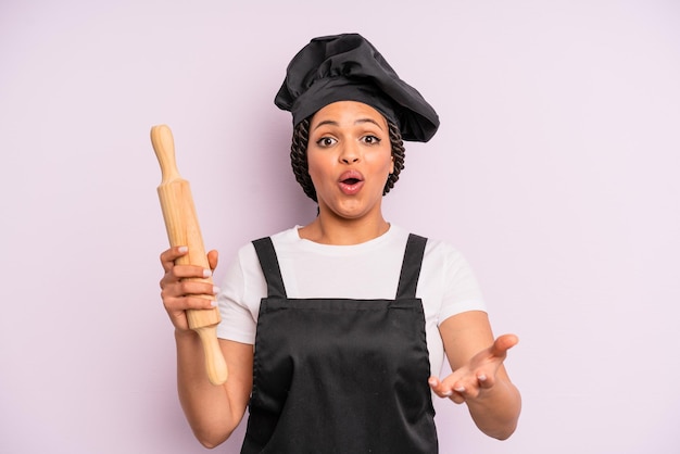 Afroschwarze Frau erstaunt schockiert und erstaunt mit einem unglaublichen Überraschungskoch mit einem Rollenstift