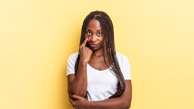 Afroschwarze hübsche Frau, die ein Auge auf dich hat, nicht vertraut, zuschaut und wachsam und wachsam bleibt