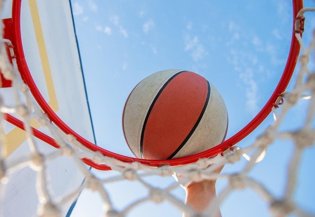 Afundando a bola de basquete através do anel da rede com a mão, basquete.