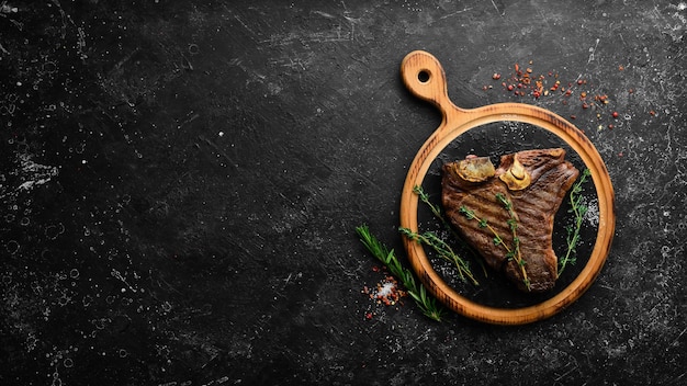 Aged Beef TBone Steak Saftig gekochtes Steak mit Rosmarin und Gewürzen Draufsicht Rustikaler Stil Flat Lay