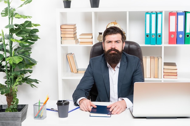 Agência de advogados Homem barbudo chefe moderno sente-se no interior do escritório poltrona de couro Chefe no local de trabalho Gerente de roupas formais estilo corporativo trabalhando Conceito de pessoas de negócios Chefe ocupado no escritório