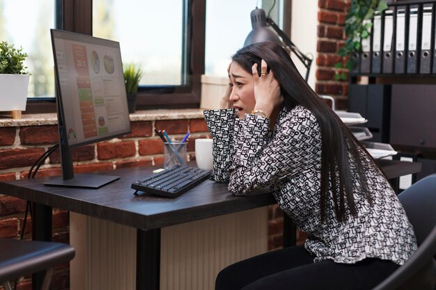 Foto la agencia de desarrollo empresarial fatiga a un empleado con dolor de cabeza por migraña sentado en un escritorio en un espacio de trabajo de oficina moderno. mujer de negocios cansada y agotada con cabeza dolorosa preocupada por la fecha límite de presentación.