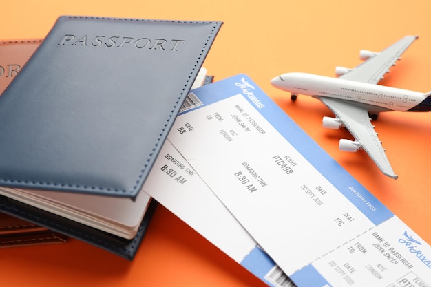 Agencia de viajes Boletos de vuelo Pasaportes y modelo de avión en primer plano de fondo naranja