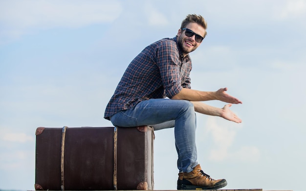 Agencia de viajes. El hombre se sienta en la maleta antes del viaje. Viaje de negocios. Viajero chico guapo. Chico al aire libre con maleta vintage. Concepto de equipaje. Viaja con equipaje. Blogger de viajes. Tiempo de vacaciones.