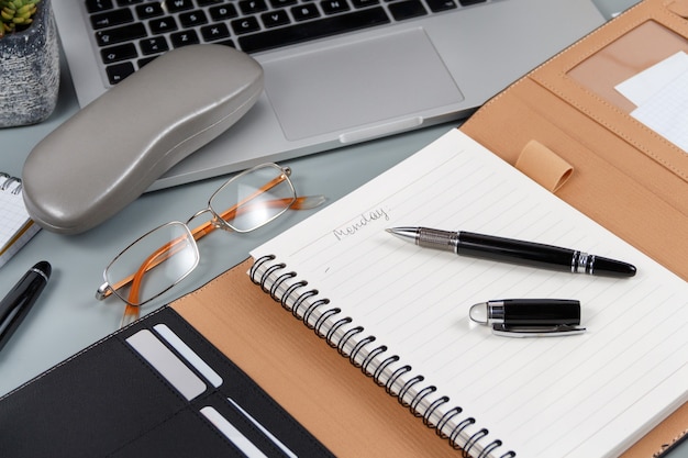 Agenda abierta con lunes escrito a mano cerca de gafas y portátil en una mesa gris de cerca