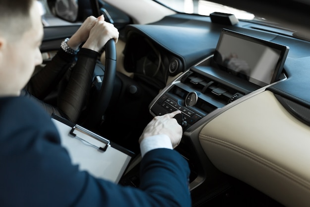 Agent und Käufer Mädchen in einem Auto in einem Autohaus. Verkäufer zeigt dem Käufer das Auto.