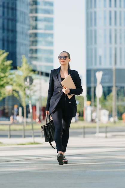 Agente de bienes raíces en un blazer está paseando con una computadora portátil en el distrito financiero