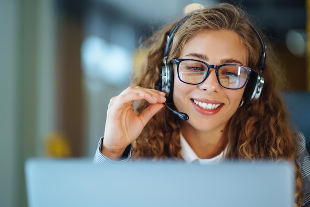 Agente del centro de llamadas con auriculares trabajando en la línea directa de soporte en la oficina moderna Videoconferencia