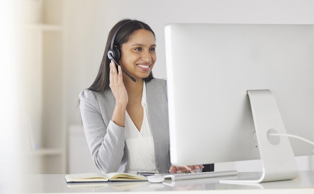 Foto agente del centro de llamadas hablando o consultando a clientes en línea con un auricular y trabajando en una computadora de escritorio en una oficina de la empresa trabajadora de atención al cliente de mujer negra que ayuda a las personas con preguntas