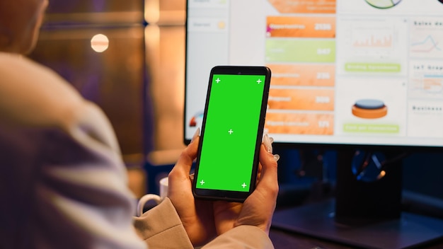 Agente consultor usando telefone celular com tela verde para trabalhar no desenvolvimento corporativo. Gerente profissional analisando modelo de copyspace isolado, exibição de chromakey de maquete em branco.