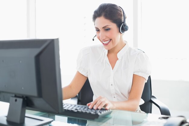 Agente de call center alegre trabalhando em sua mesa em uma chamada