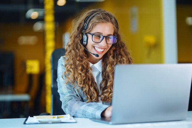 Agente de call center com fone de ouvido trabalhando na linha direta de suporte no escritório moderno Videoconferência