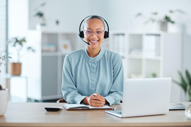 Agente de call center feliz e confiante sentado na frente de um laptop enquanto usa um fone de ouvido em um escritório Retrato de uma vendedora alegre usando bate-papo na web para ajudar nas vendas ao cliente e suporte de serviço