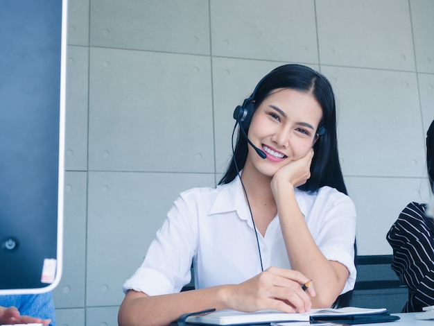 Agente de mulher amigável operador com fones de ouvido trabalhando em um call center