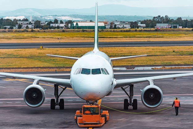 Agente de rampa de execução de avião acompanha operação de push back no aeroporto