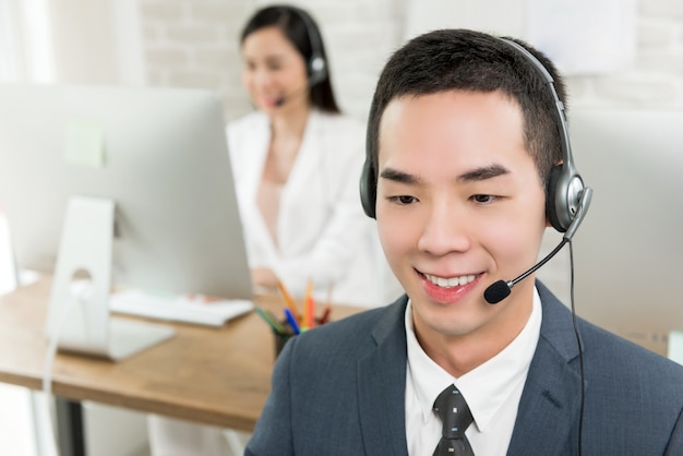 Agente de telemarketing de serviço ao cliente asiático masculino sorridente em call center