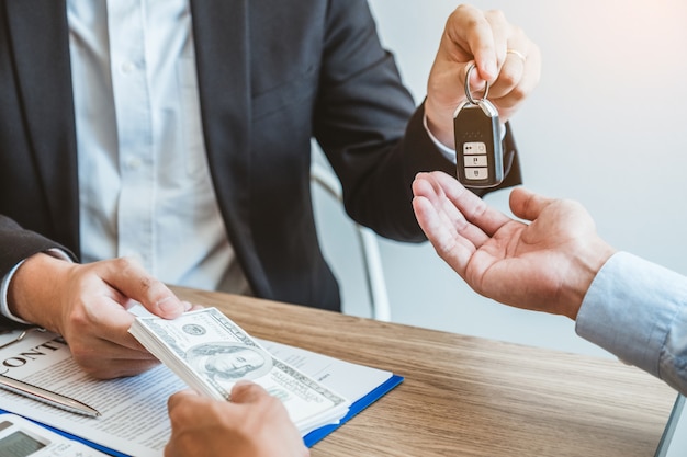 Agente de venda que dá a chave do carro ao cliente e assina o contrato do acordo, conceito do carro do seguro.