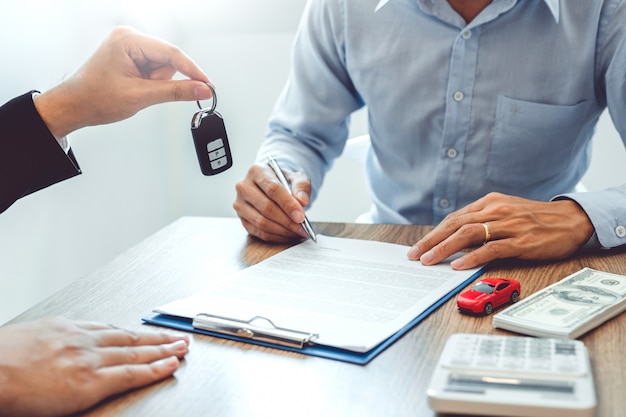 Agente de vendas, dando a chave do carro ao cliente e assinando contrato