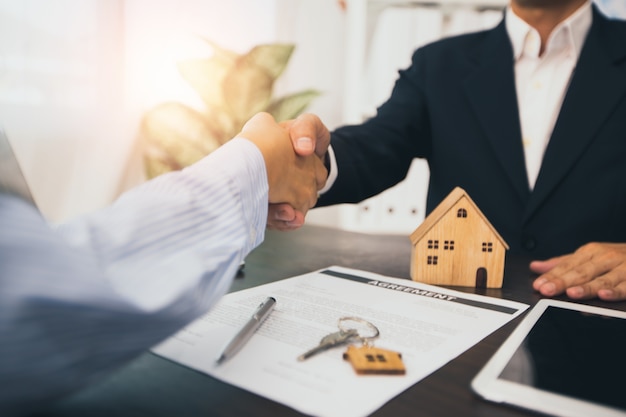 Foto agente doméstico se da la mano con el cliente después de firmar el contrato