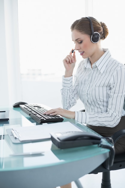 Agente feminino concentrado sentado em sua mesa com fone de ouvido