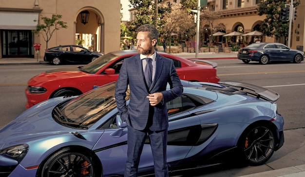 Agente imobiliário de homem bonito em terno formal em pé perto do seguro automóvel de luxo