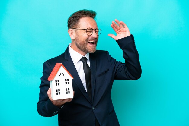 Foto agente imobiliário de meia-idade isolado em fundo azul sorrindo muito