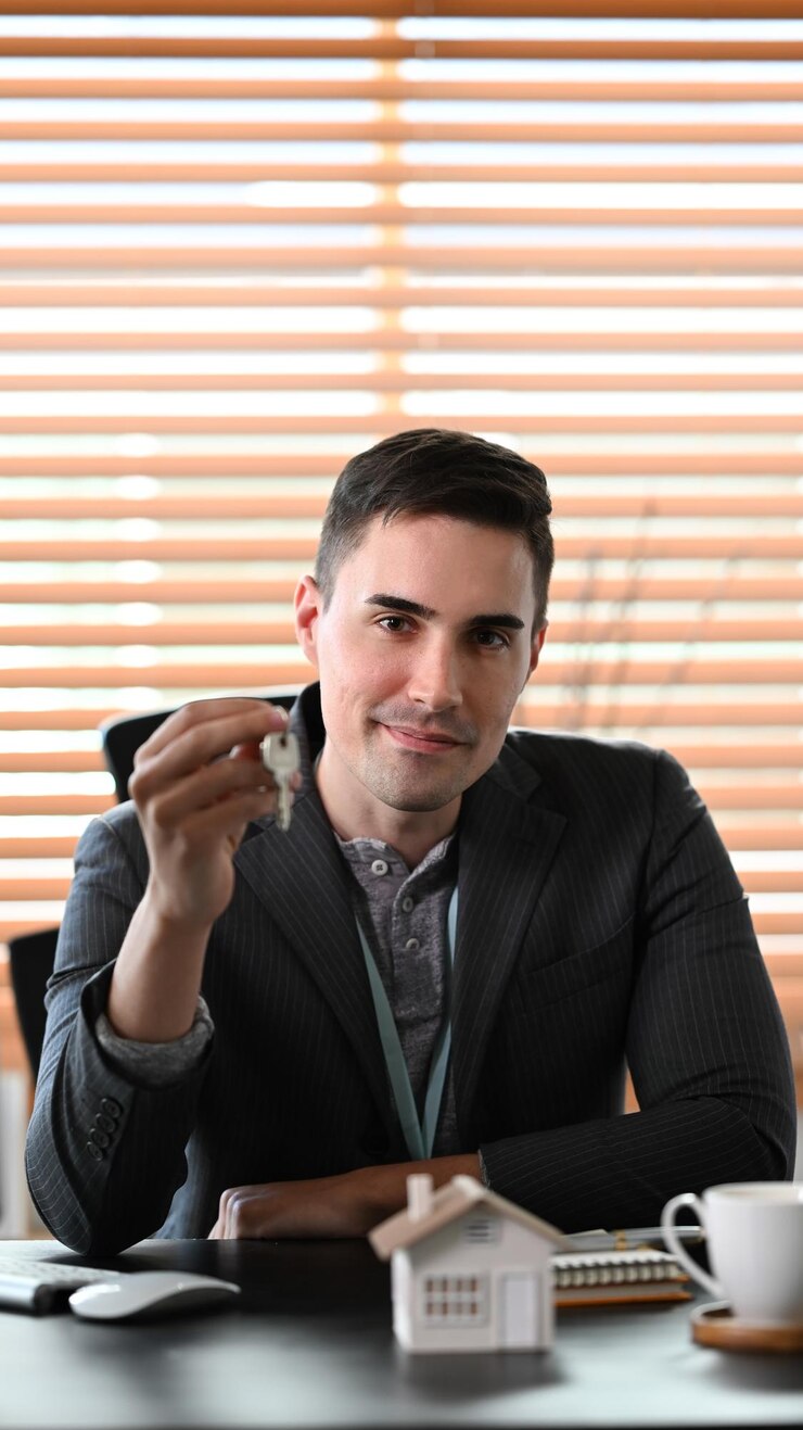 Foto agente imobiliário de retrato segurando a chave da casa e sorrindo para a câmera conceito de seguro ou empréstimo imobiliário