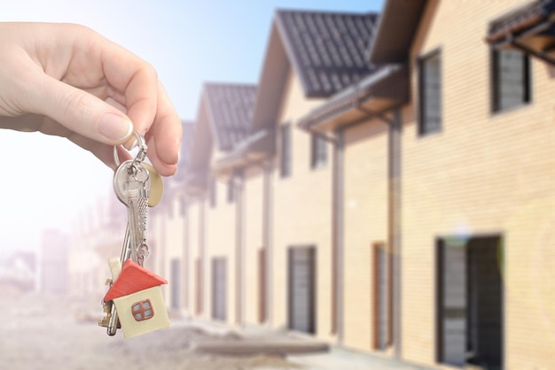 Agente imobiliário entregando uma chave de casa Chave com um chaveiro em forma de casa no novo fundo de casa Conceito de hipoteca