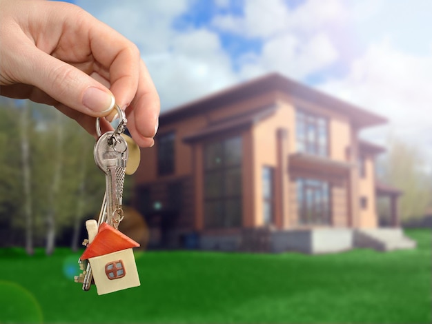 Agente imobiliário entregando uma chave de casa Chave com um chaveiro em forma de casa no novo fundo de casa Conceito de hipoteca