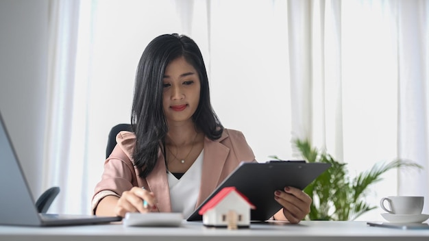 Agente imobiliário focado usando calculadora e trabalhando na mesa de escritório