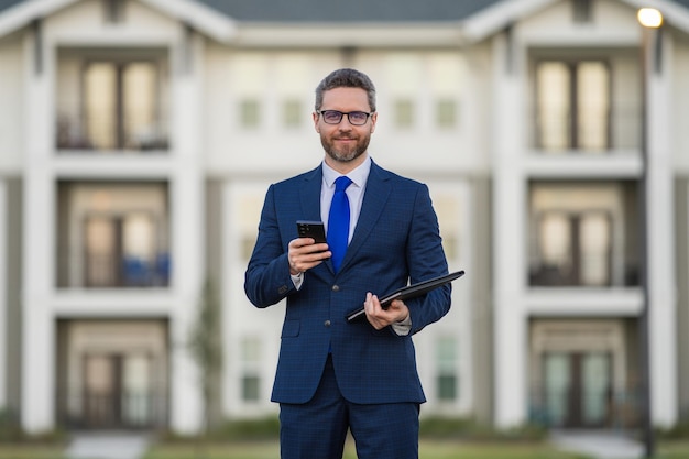 Foto agente imobiliário homem de negócios em terno segurar clipboards e falar ao telefone homem de negócios