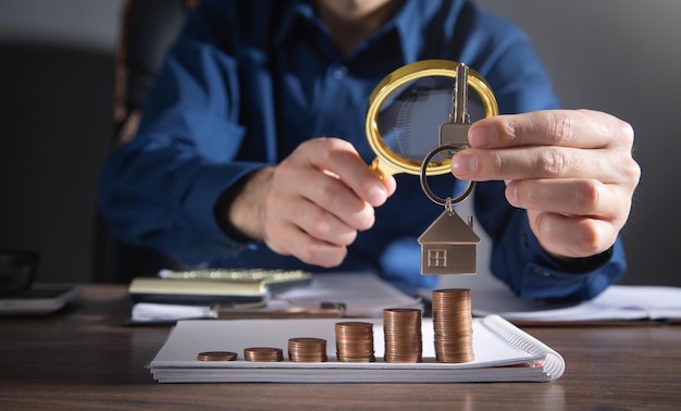 Foto agente imobiliário mostrando a chave da casa sobre a pilha de moedas