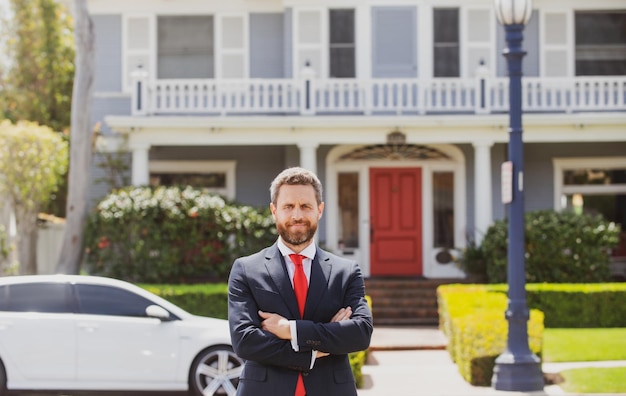 Agente imobiliário pronto para vender empresário em casa do lado de fora de uma casa moderna